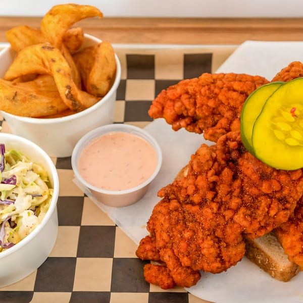 Flew the Coop Nashville Hot Chicken tenders with pickles, coleslaw, potato wedges, and dipping sauce.