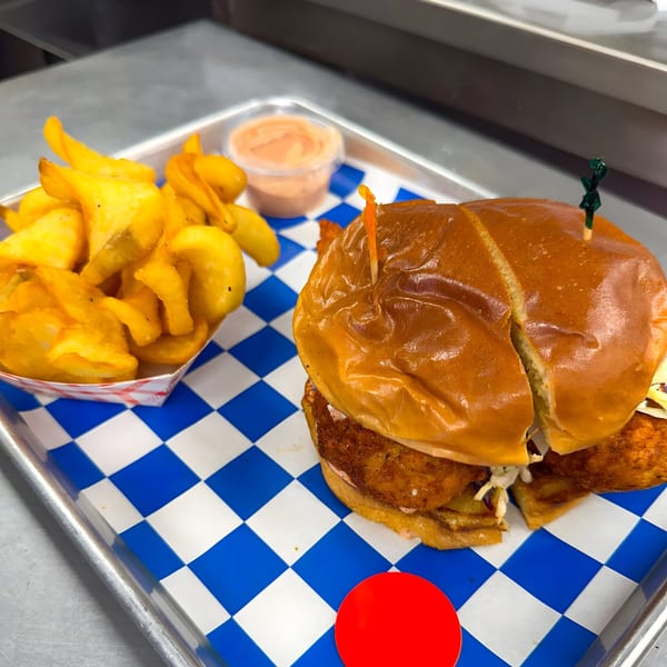 Flew the Coop Nashville Hot Chicken Shack's fried chicken sandwich with fries and dipping sauce on a tray.